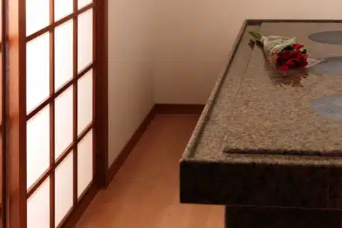 A bouquet of red and white roses rests on a granite countertop in a room with wooden floors and a shoji-style sliding door.