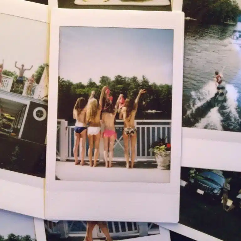 Five people in swimming costumes stand on a deck, facing away from the camera, with trees and water in the background, capturing a carefree moment on Valentines 2017.
