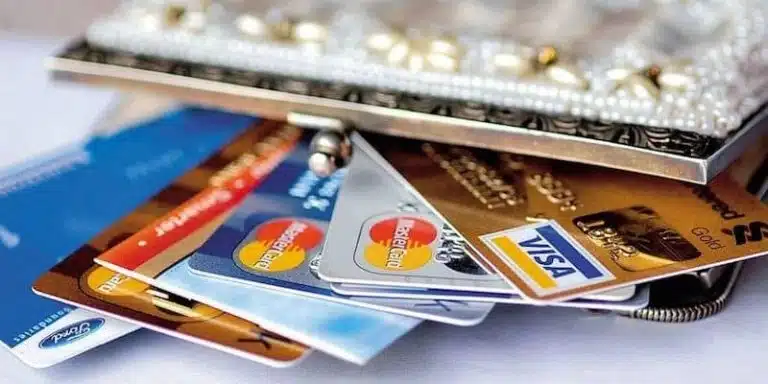A close-up of several credit and debit cards, including a limited edition GSS 2017 card, partially pulled out from a decorative purse.