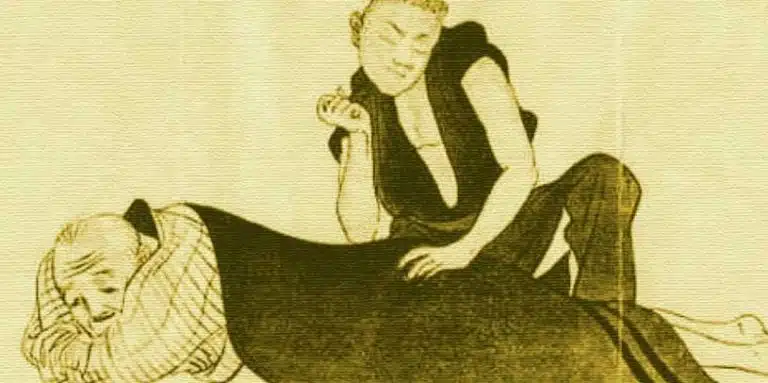 A person lies face down on the floor whilst another kneels beside them, using one knee to press on their back and holding their armβdemonstrating a massage therapy technique.