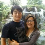 A man and a woman enjoying a serene moment at a Japanese spa's onsen, surrounded by the beauty of a waterfall.
