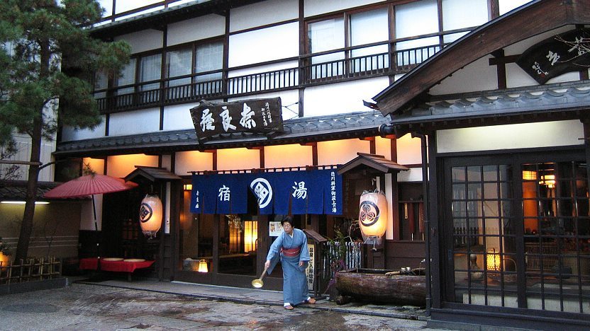 A woman is standing outside of a Japanese restaurant.