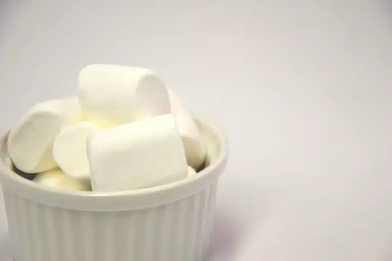 A white ramekin filled with large white marshmallows sits against a plain white background, perfect for a cosy white Valentine's Day treat.