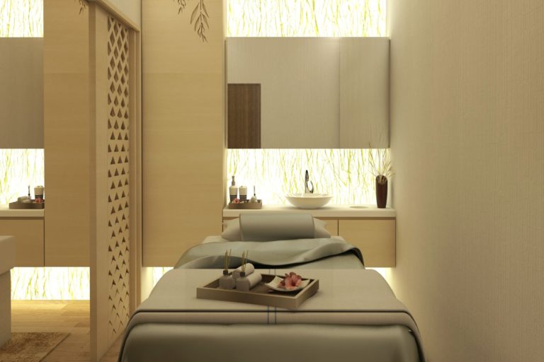 A tranquil spa treatment room featuring a bed with a tray of spa essentials, a sink with a mirror, and a serene ambiance with soft lighting and minimalist decor perfect for experiencing massages in Singapore.