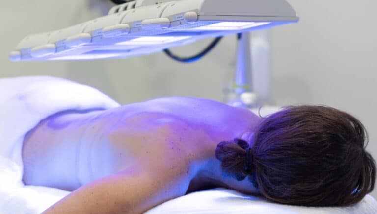 Back acne treatment for women lying on the bed with blue light LED