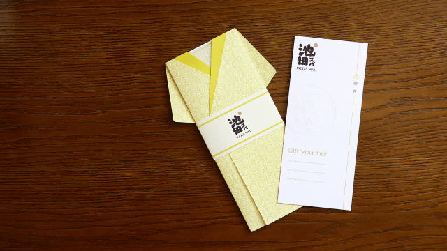 A Japanese kimono gracefully draped over a wooden table, along with a card holding a Singapore Spa Voucher.