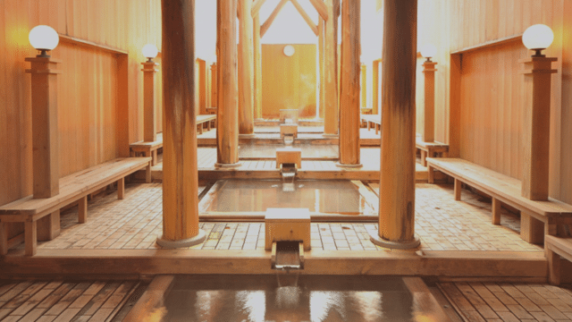 A serene interior of a tattoo friendly onsen features Japanese-style wooden bathhouse elements, including hot spring baths, wooden beams, benches, and soft lighting from lanterns.