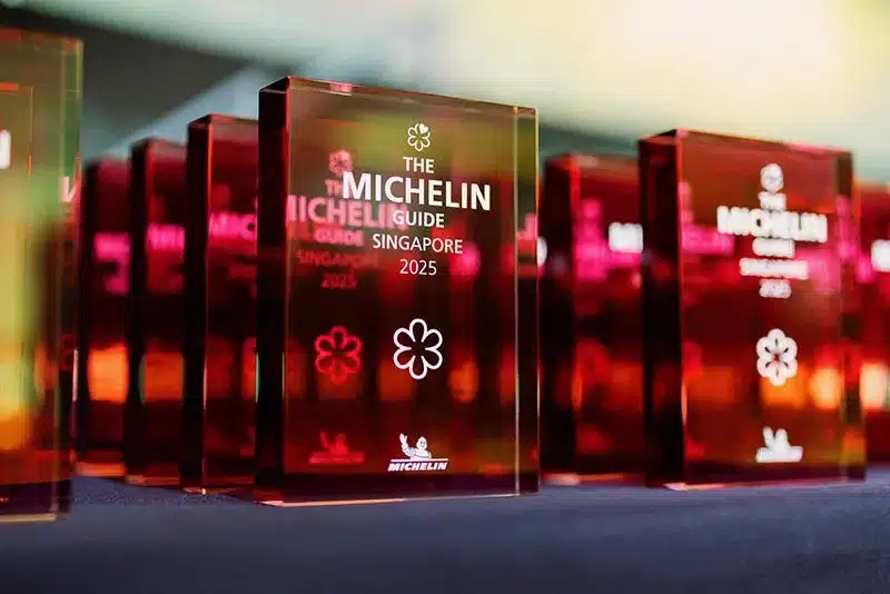 A row of red acrylic plaques displaying the Michelin Guide Singapore 2025 logo and a Michelin star, honoring a top Japanese restaurant in Singapore, arranged on a dark surface.