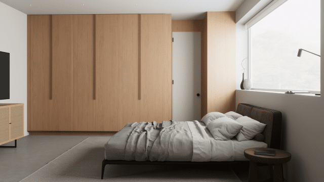 A modern bedroom featuring a low-profile bed with gray bedding invites calm, while the wooden wardrobe and window offer sleek practicality. A floor lamp casts gentle light beside a small round side table—ideal for those seeking a serene retreat as part of their insomnia treatment.