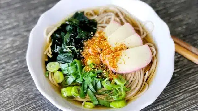 A bowl of noodle soup topped with sliced fish cake, chopped spring onions, seaweed, and seasoning—a comforting dish enjoyed in Japan and often served to celebrate occasions like Chinese New Year.