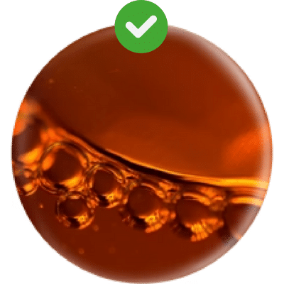 A close-up of oil bubbles in a circular container, reminiscent of an onsen facial experience, with a green checkmark overlay at the top.