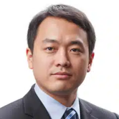 A man in a suit and tie poses for a headshot against a plain white background.