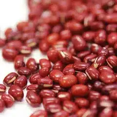 Close-up of red adzuki beans scattered on a white surface, evoking the warmth and colour of a Christmas spa retreat.