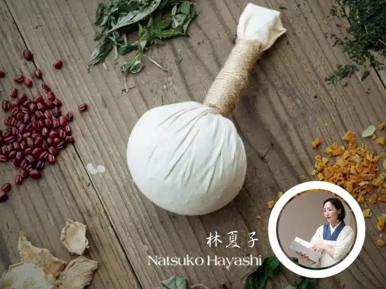 A white herbal compress ball on a wooden surface, surrounded by dried herbs and seeds; inset shows a woman in traditional clothing, reading. Text reads "Natsuko Hayashi." Perfect for a relaxing Christmas spa retreat.
