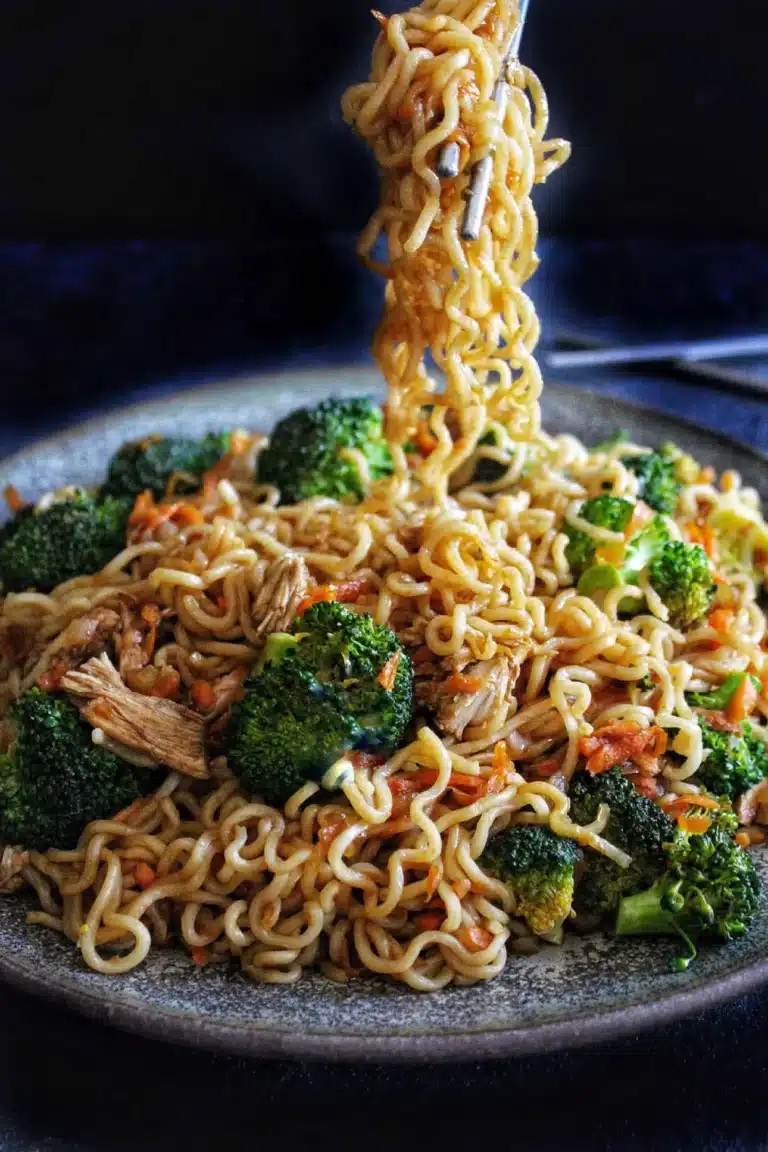 A plate of cooked ramen noodles with broccoli and shredded meat, with a fork lifting a portion of noodles, evokes the comforting flavours of a Japanese meal—perfectly complemented by a refreshing bottle of ramune on the side.