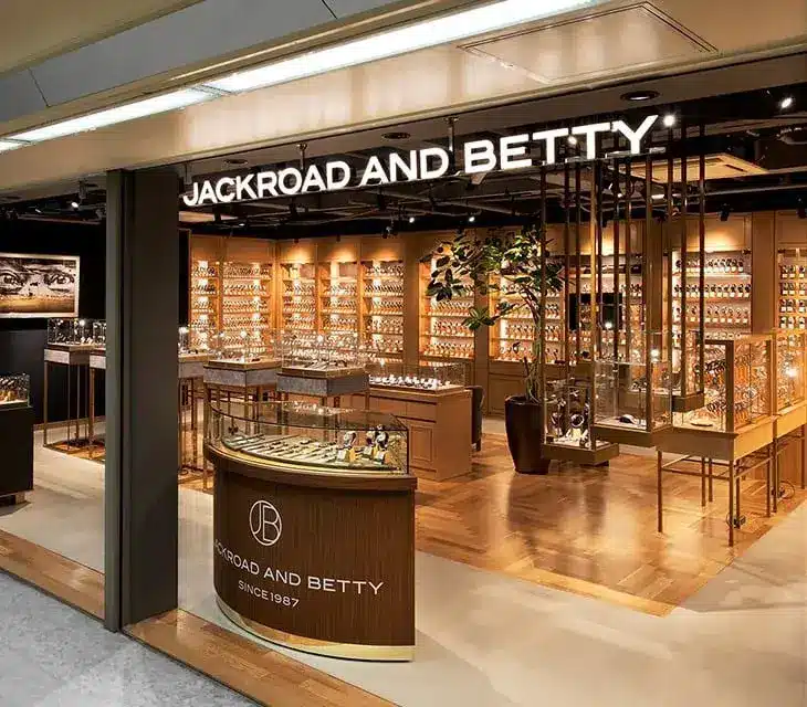 The shopfront of Jackroad and Betty displays shelves filled with watches, including elegant Grand Seiko timepieces, and a glass counter, with warm lighting highlighting the products inside.